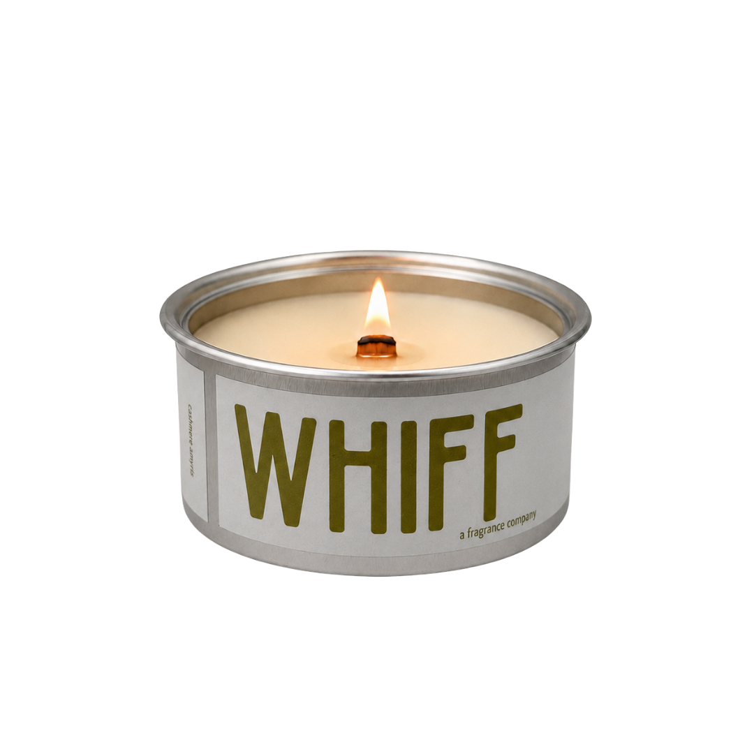 A lit tin martini candle with cream-colored wax and a silver metal rim, featuring the word 'WHIFF' in olive green text on the front label, set against a plain white background.